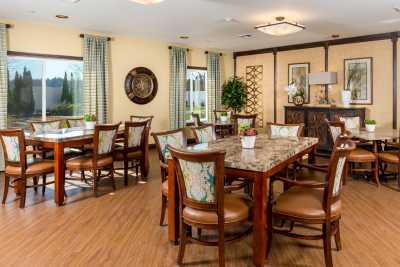A cozy dining room with multiple tables and chairs, decorated with elegant curtains and lighting.