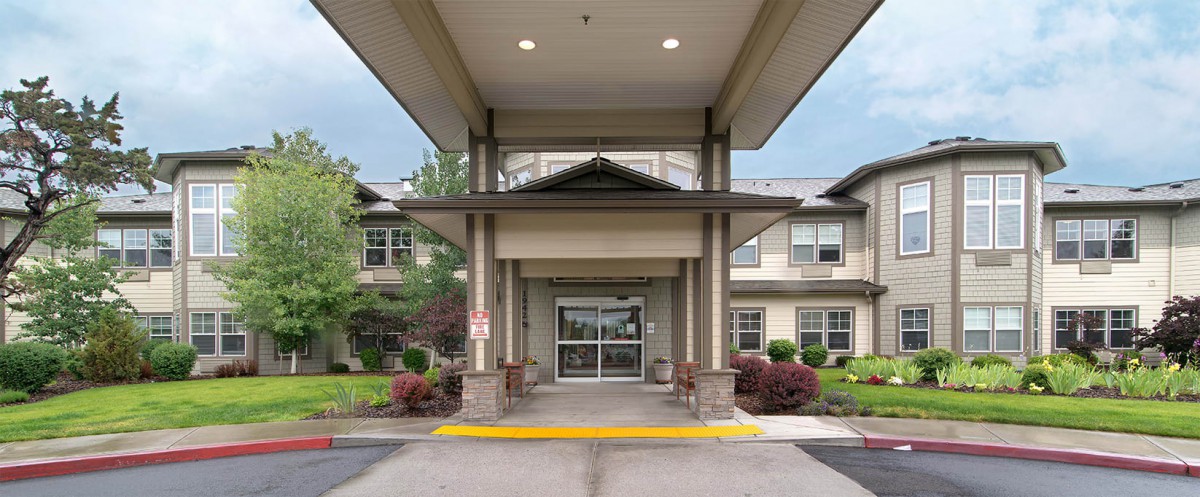The entrance of a modern building with well-maintained landscaping.