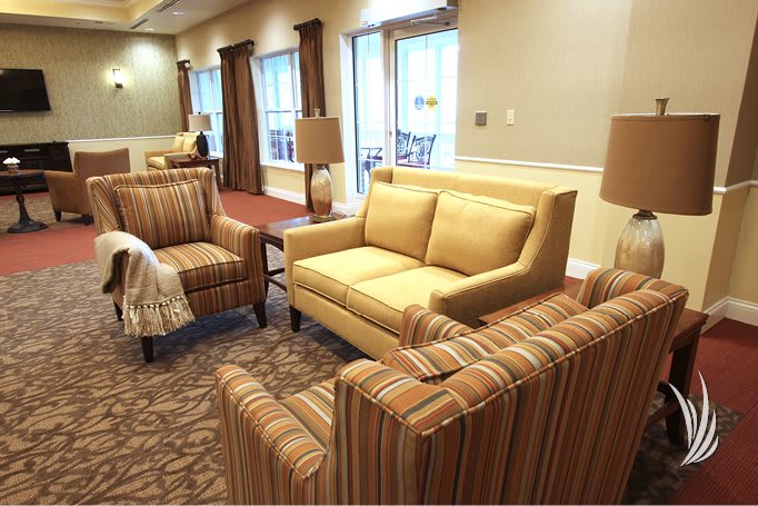A cozy living room setup featuring a sofa, striped chairs, and a coffee table with lamps.