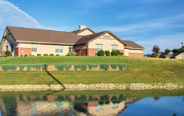 A house by a lake with reflections in the water and a clear blue sky.