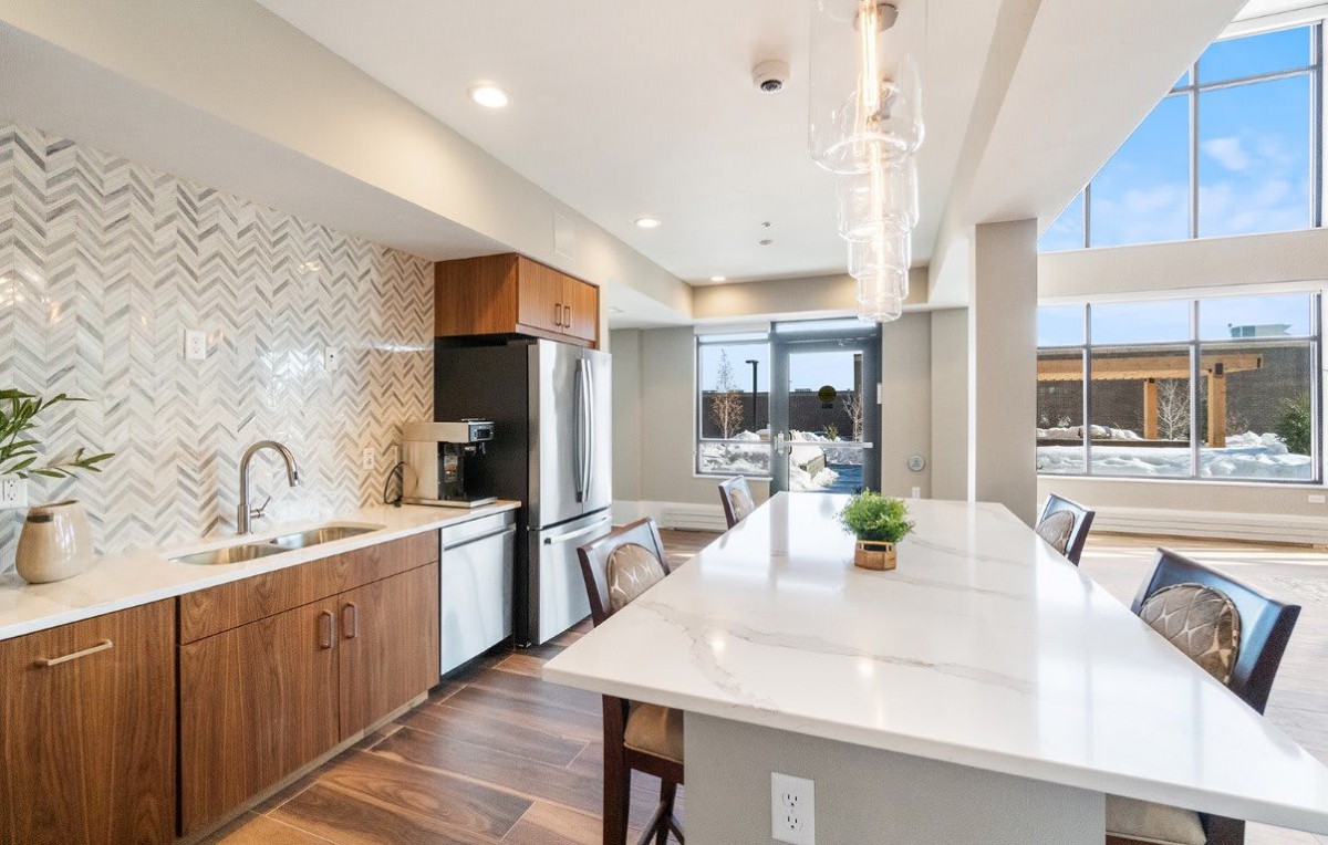 Modern kitchen with an island counter, featuring wood cabinets and contemporary lighting.