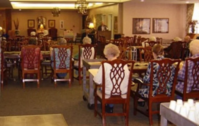 A group of elderly people seated in a dining area of a community center.