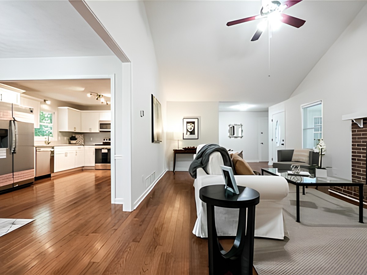 A modern open-concept living room with hardwood floors and a view into the kitchen.