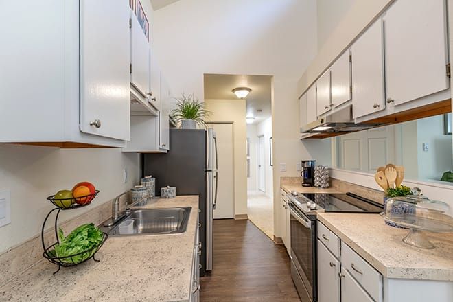 A modern galley-style kitchen in an apartment with sleek countertops and cabinets.