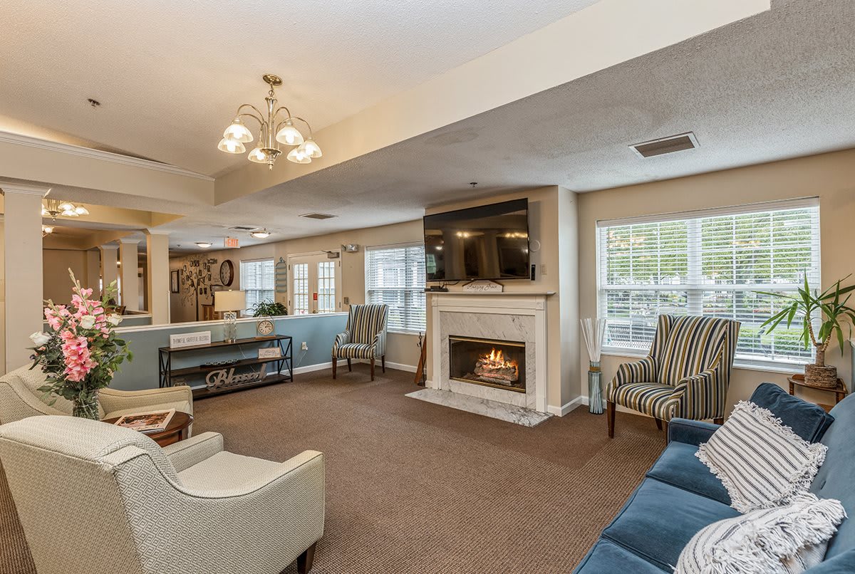 A cozy living room with a fireplace, multiple seating options, and a television mounted above the mantel.
