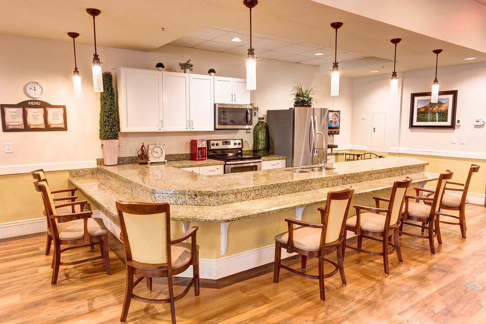 A modern kitchen with a large countertop and upholstered chairs.