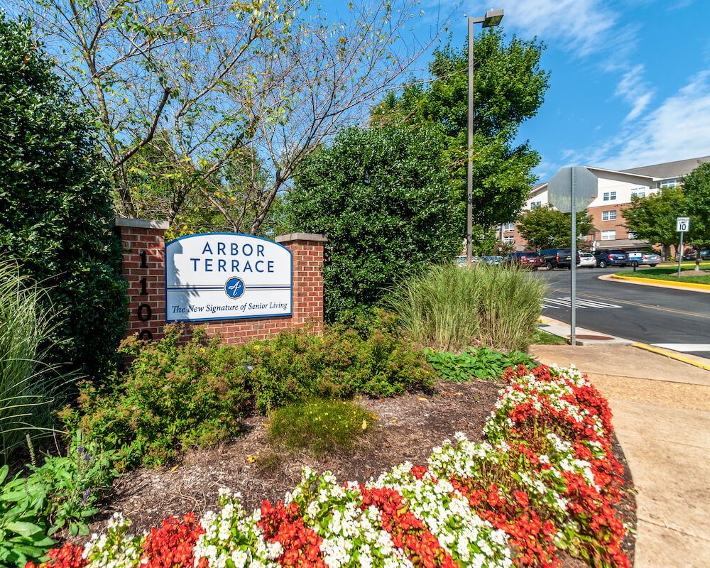 Entrance sign for Arbor Terrace surrounded by landscaped flowers and greenery.