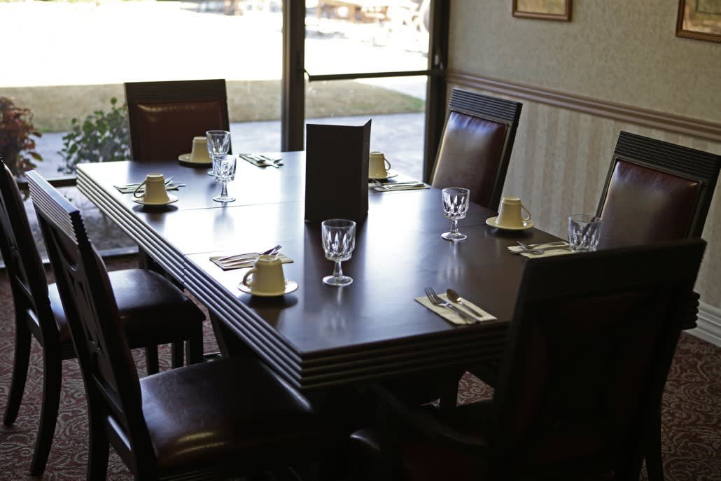 A neatly set dining table in a restaurant with glasses, cutlery, and napkins.