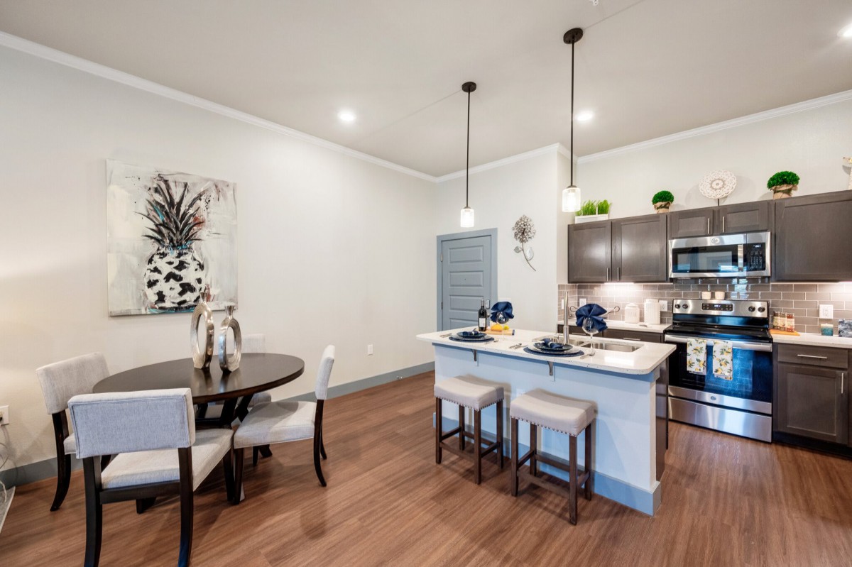A modern open-concept kitchen and dining area featuring an island counter and pendant lighting.