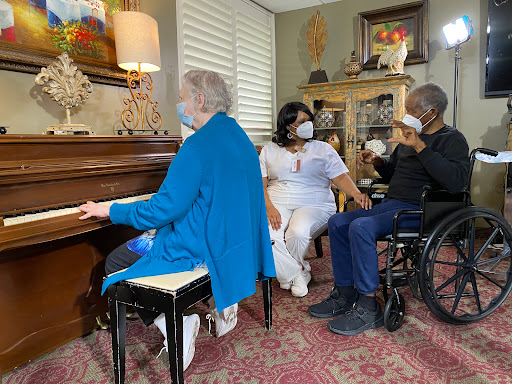 A group of elderly individuals enjoying a musical moment together, with one person playing the piano.
