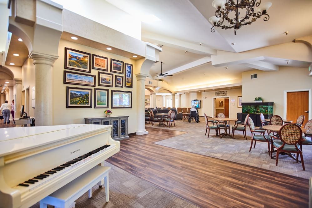 A spacious living room with a grand piano, artwork on the walls, and a cozy seating area.