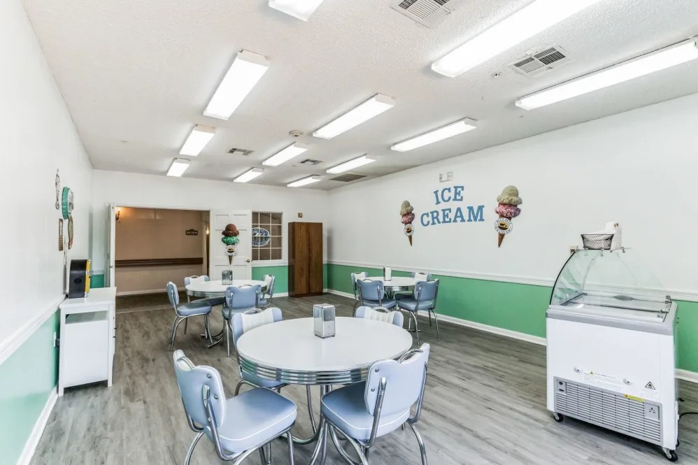A cozy ice cream shop interior with tables and chairs under bright lighting.