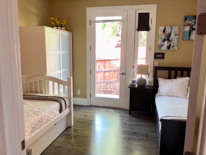 A cozy bedroom with twin beds and a door leading outside.