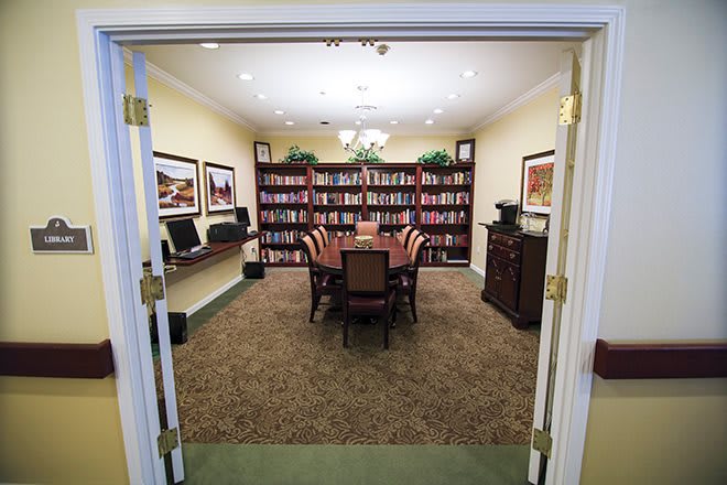 A well-organized library room set up for meetings, featuring bookshelves and a central conference table surrounded by chairs.