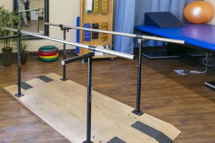 A physical therapy room featuring parallel bars used for rehabilitation exercises.