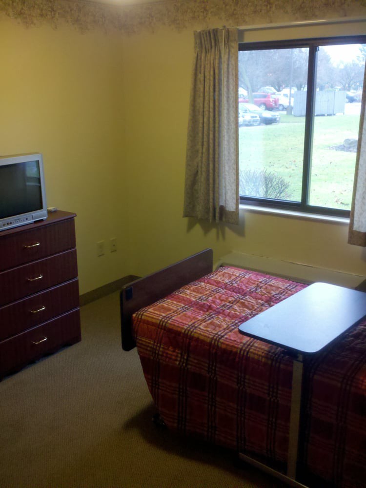 A small room with a single bed, television, and a window offering an outside view.
