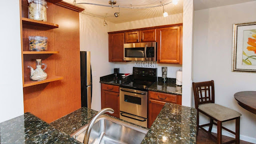 A modern kitchen featuring wooden cabinets, stainless steel appliances, and a granite countertop.
