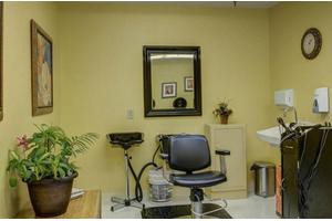 A cozy hair salon setup with a chair, mirror, and sink.