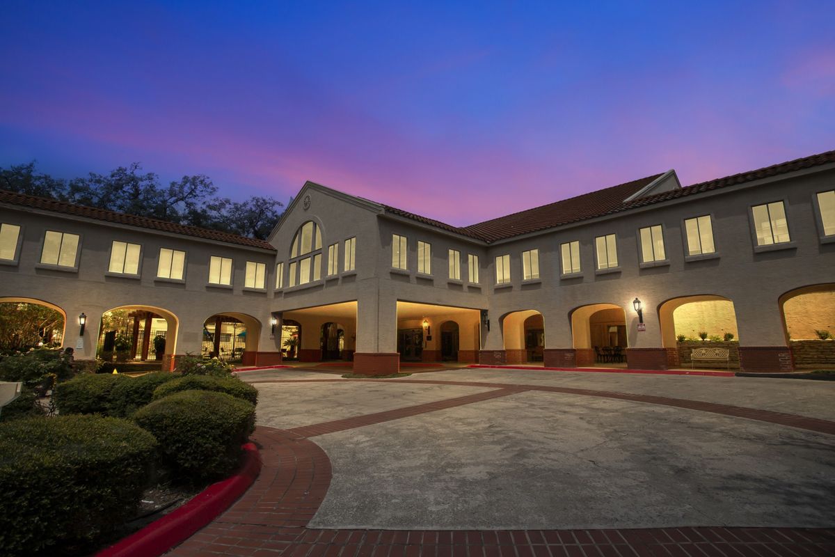 A well-lit building with a courtyard captured at dusk.