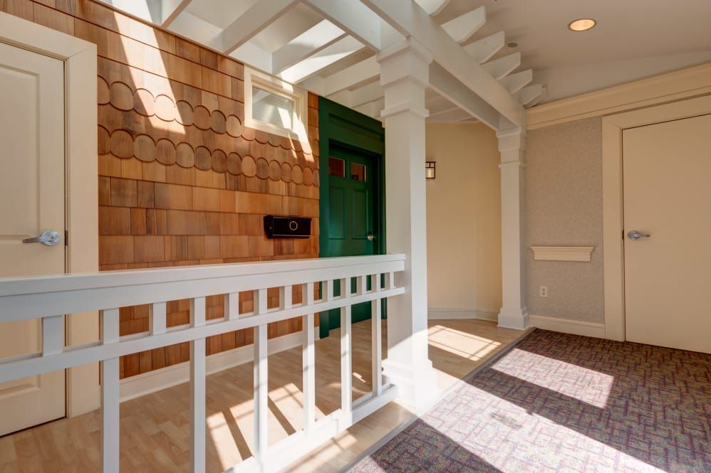 A sunlit porch featuring a green door and wooden paneling.