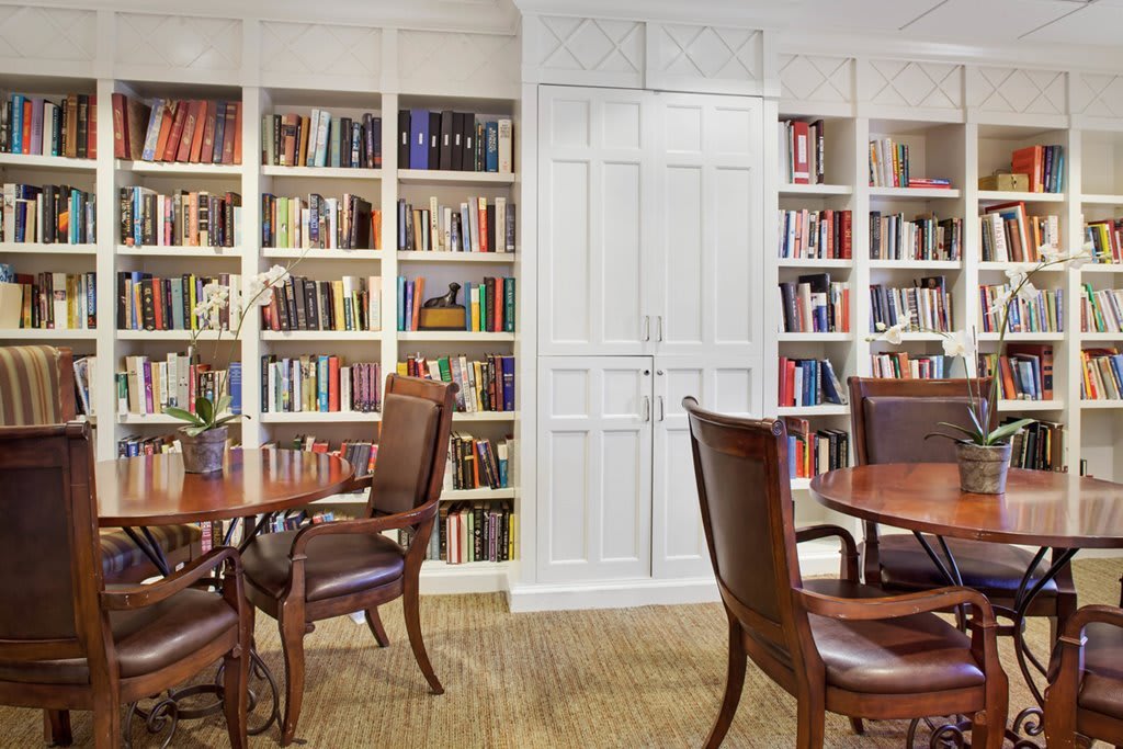 A cozy library space with bookshelves, wooden tables, and chairs for reading and study.