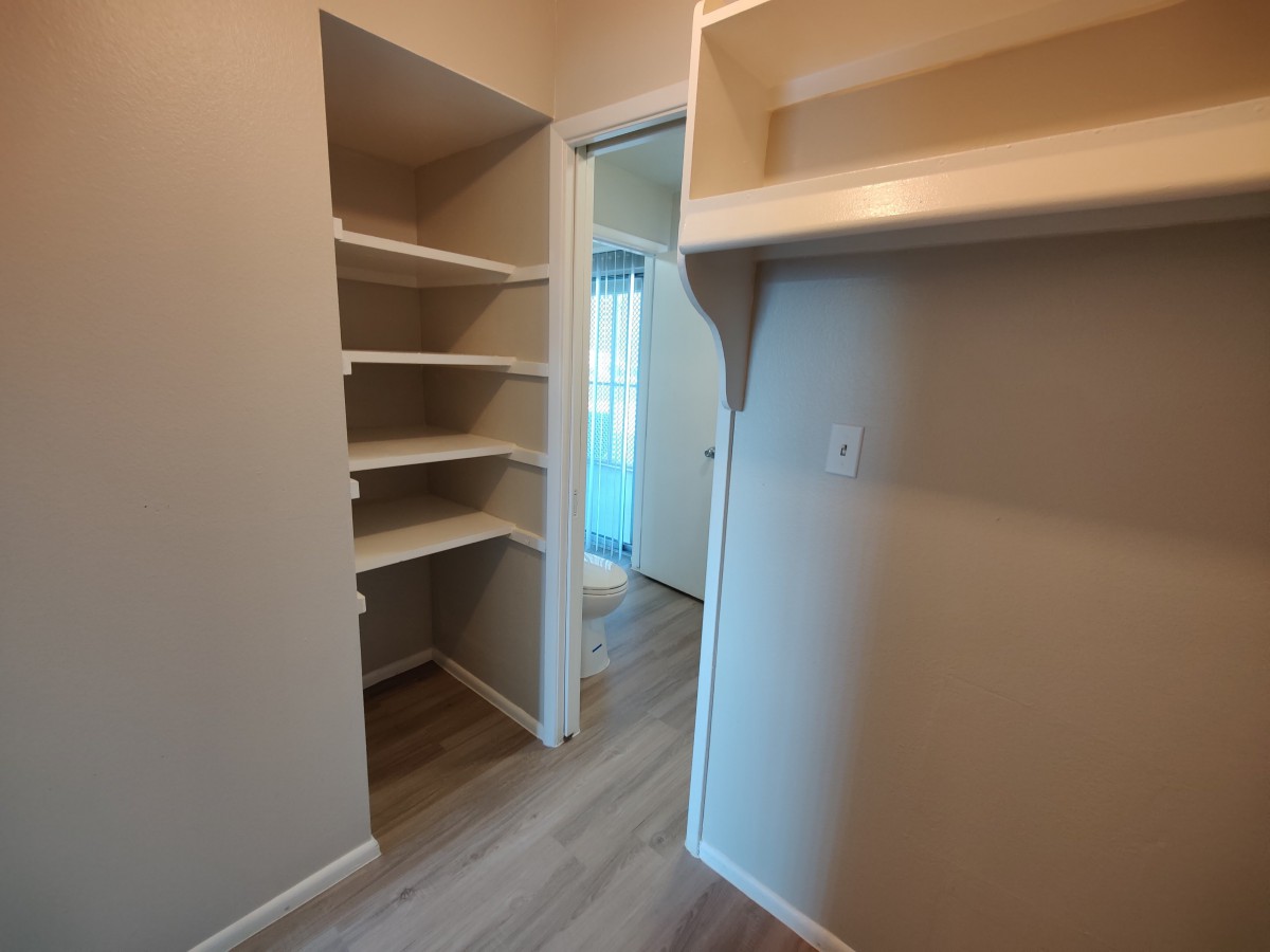 An empty walk-in closet featuring built-in shelves and hanging space.