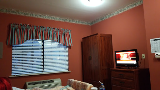 A cozy bedroom featuring a warm wall color, simple furniture, and a television.