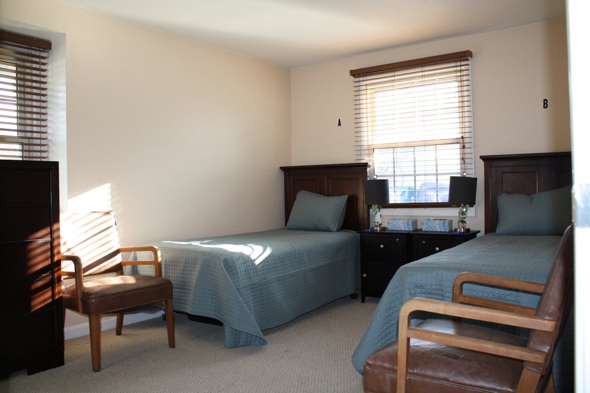 A minimalist bedroom with twin beds and simple furnishings.