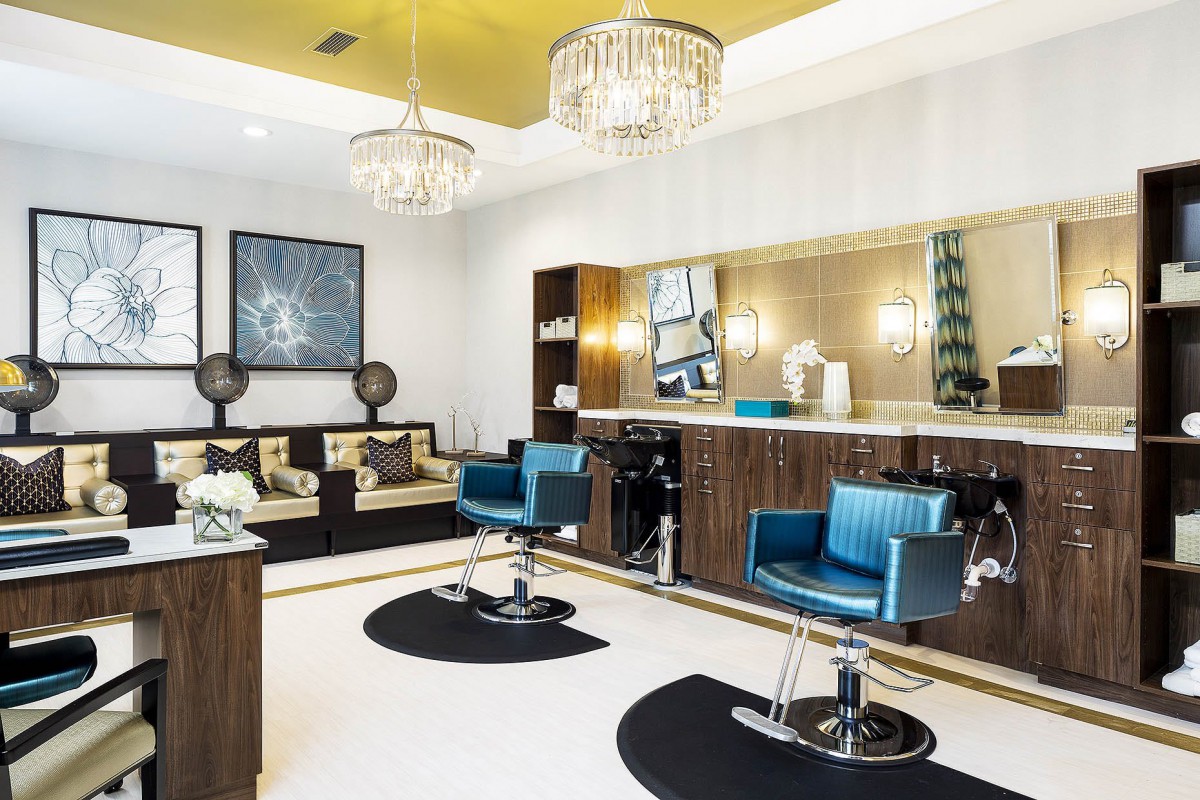 A modern, stylish salon interior with blue chairs and elegant chandeliers.