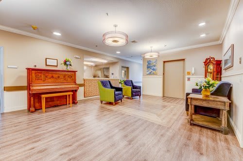 A cozy lounge area featuring a wooden piano, plush chairs, and ambient lighting.