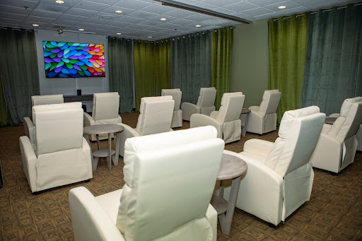 A modern lounge area featuring comfortable recliner chairs and a large TV, designed for relaxation.