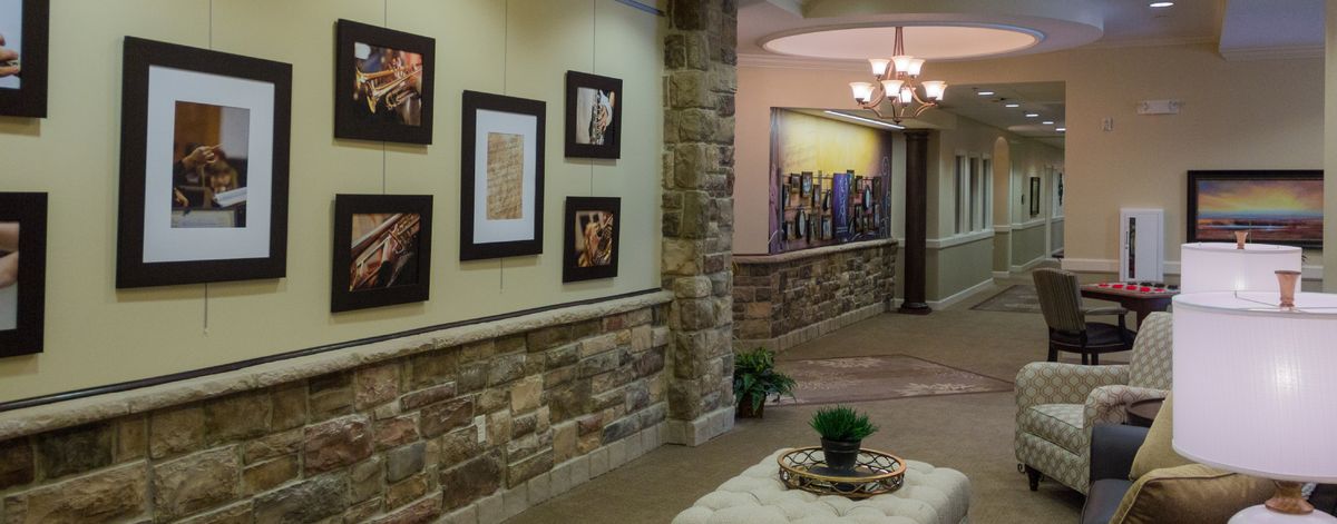A stylish hallway features framed artwork on the walls, stone accents, and elegant lighting fixtures.