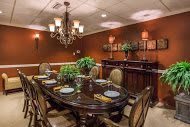 A warmly lit, elegant dining room with a chandelier and a set dining table.