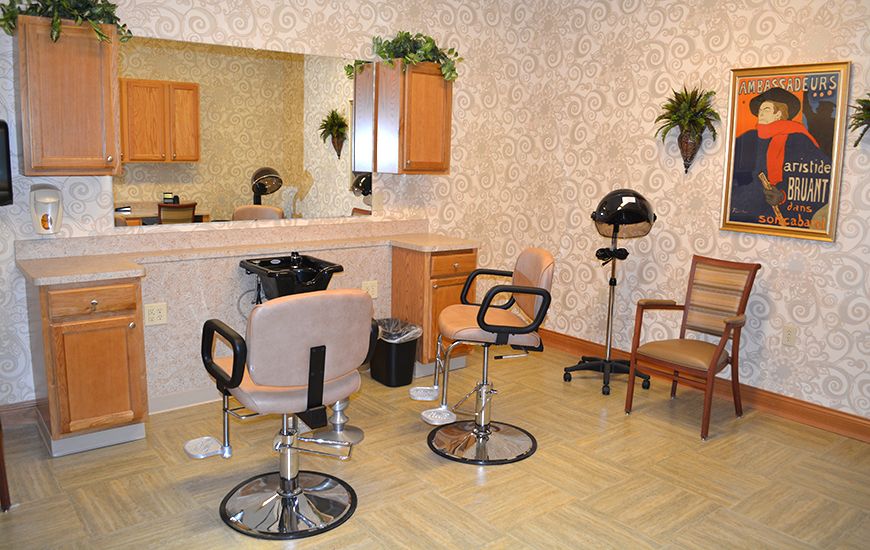 An interior view of a hair salon with styling chairs, a large mirror, and a hair dryer.
