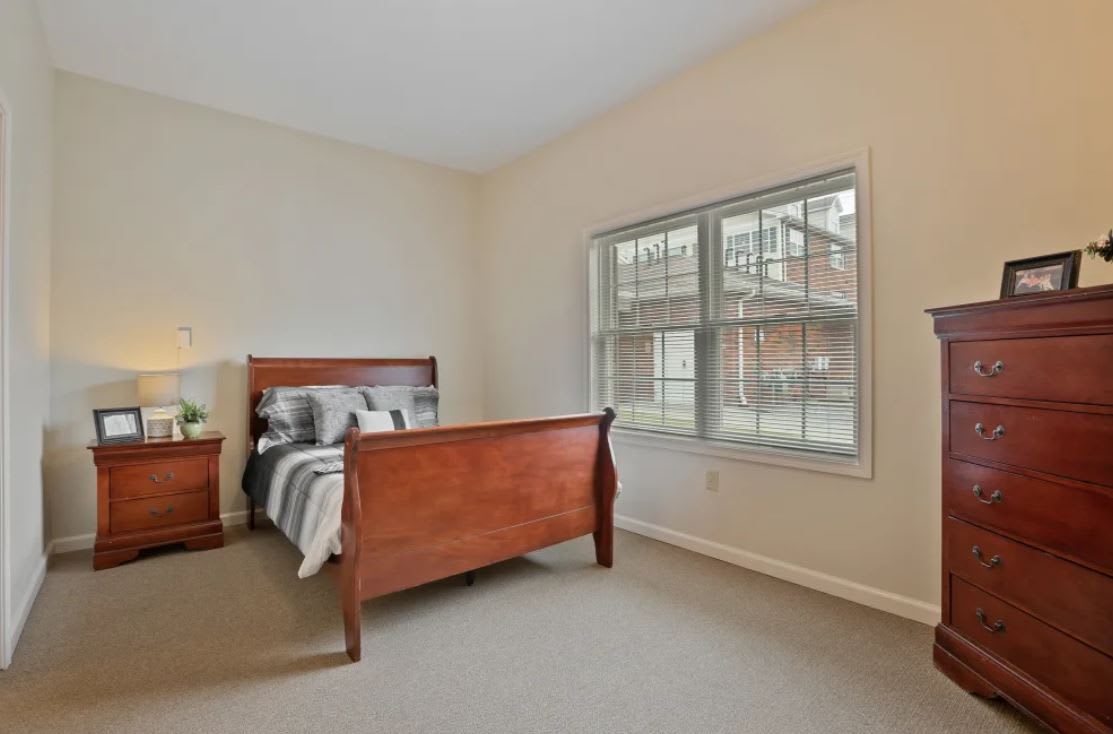 A cozy bedroom with a wooden bed and large window.
