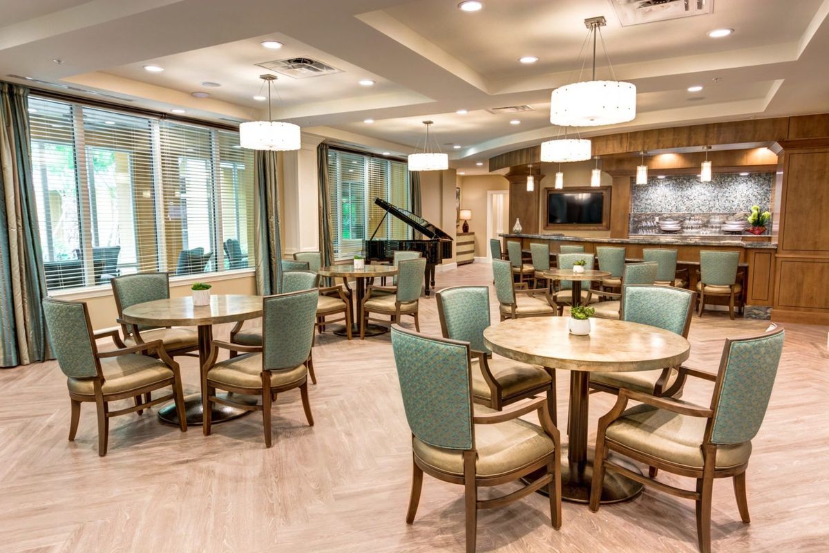 A modern dining area featuring elegant tables and chairs, with a piano in the corner and stylish lighting.