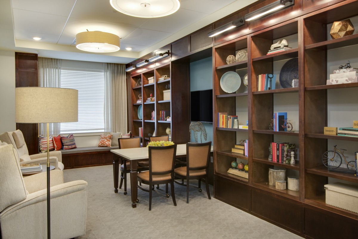 A modern living room with bookshelves, a dining table, and cozy seating.
