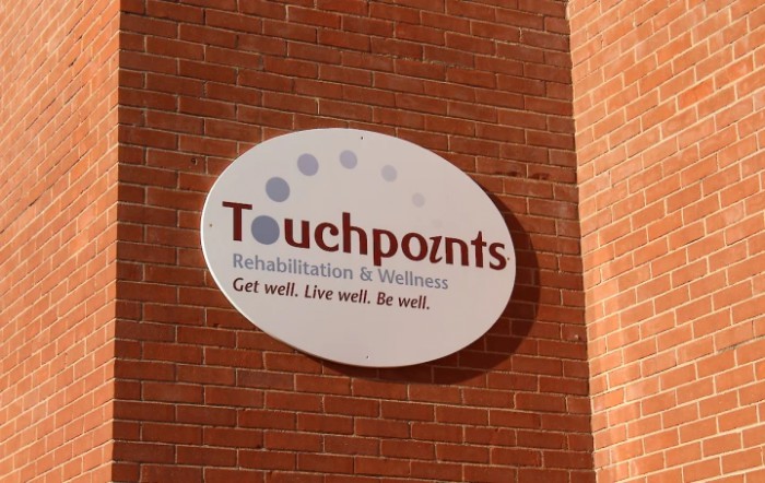 Sign for Touchpoints Rehabilitation & Wellness on a brick wall.