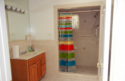 A bright and colorful bathroom featuring a shower with a striped curtain and a wooden vanity.