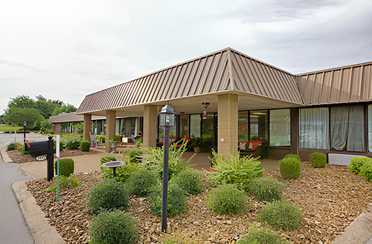 A modern building with a landscaped garden in front, featuring large windows and a triangular roof.