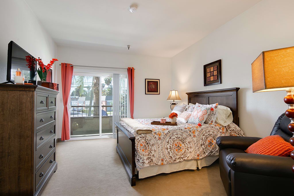A cozy bedroom with a large bed, stylish decor, and a window with red curtains.