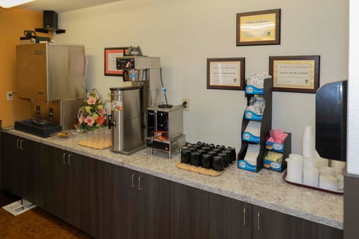 A well-equipped coffee station with a variety of beverage options and certificates displayed on the wall.