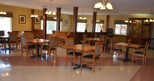 A cozy dining area featuring wooden tables and chairs, with warm lighting creating an inviting atmosphere.