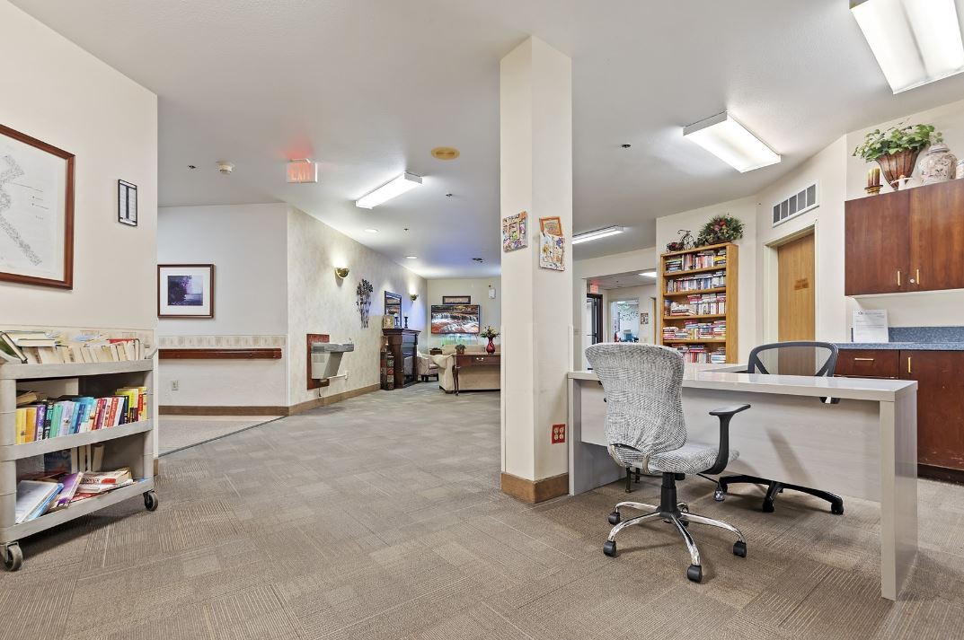 A spacious office interior with desks, chairs, and bookshelves in a reception area.