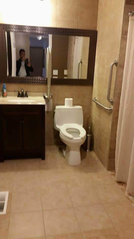 A clean and accessible bathroom with a toilet, sink, and mirror.