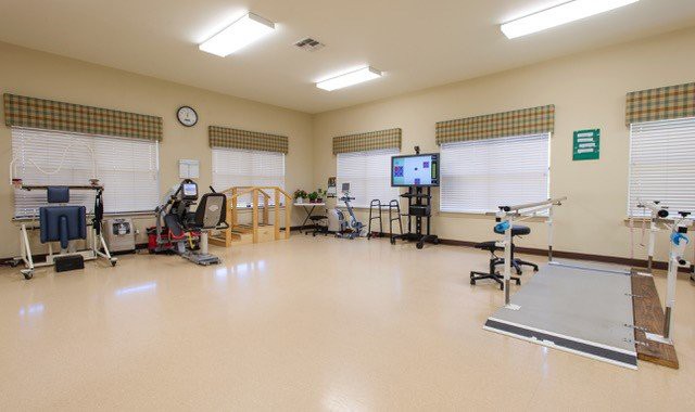 A spacious physical therapy room equipped with various exercise machines and rehabilitation tools.