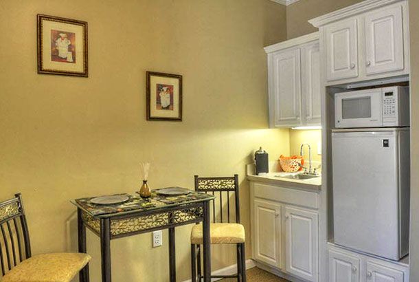 A cozy kitchen corner with a small dining table and chairs next to white cabinets.