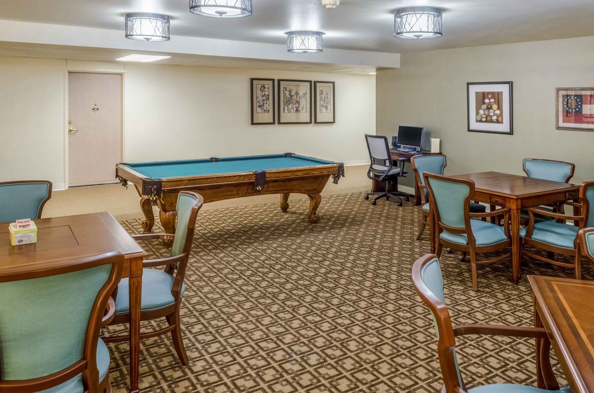 A game room with a billiard table, seating area, and computer station.