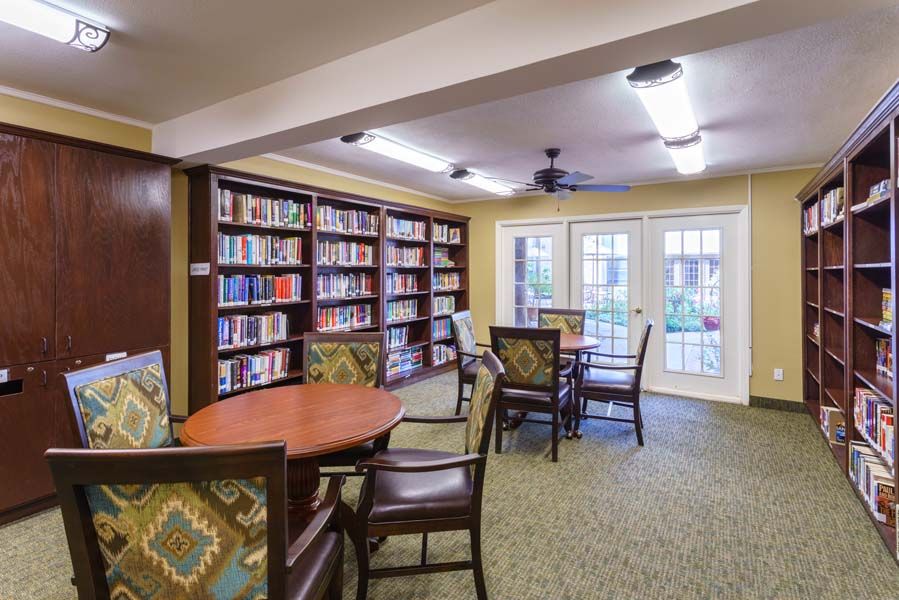 A cozy library room with bookshelves, tables, and chairs.