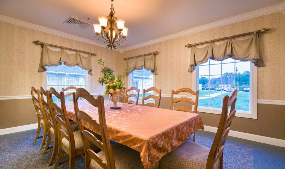 A warmly lit dining room with a large table, chairs, and elegant decor.